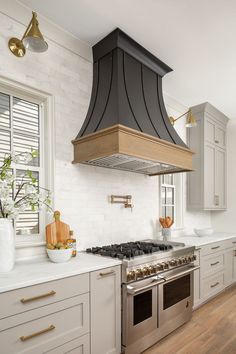 a stove top oven sitting inside of a kitchen next to white cabinets and wooden floors