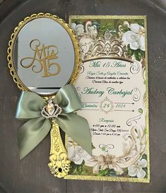 the wedding card is decorated with gold and green ribbon, which has a monogram on it