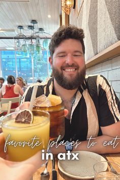 a man sitting at a table with two drinks in front of him and the words favorite places to eat in atx