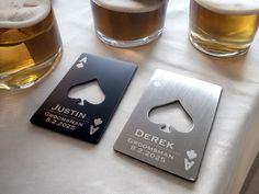 two beer coasters sitting on top of a table next to some glasses filled with beer