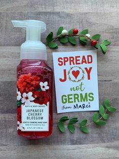 a bottle of hand sanitizer next to a card and some flowers on a wooden table