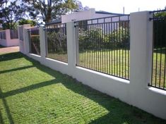 a white fence with black iron bars on it and grass in the yard behind it