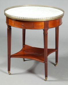 an oval table with marble top and brass trim