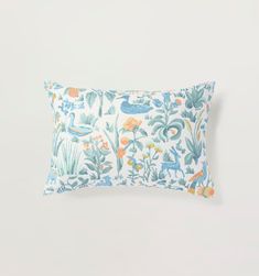 a blue and orange floral pillow on a white background with an image of birds in the sky