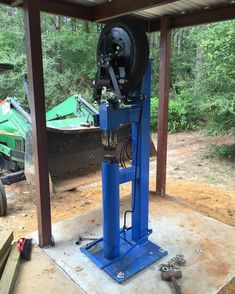 a machine that is sitting in the middle of some dirt and wood with trees in the background