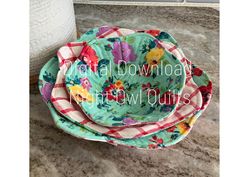 three flowered dishes sitting on top of a counter next to a roll of toilet paper