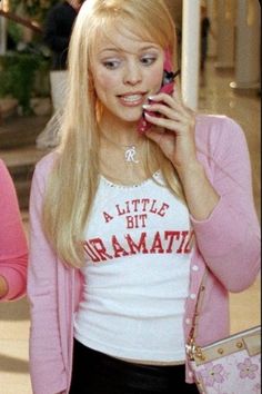 a woman talking on a cell phone while wearing a pink cardigan and black skirt