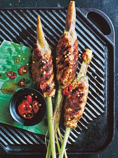 grilled meats and vegetables on a grill with dipping sauce in a small bowl