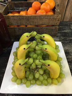 bananas and oranges are arranged in the shape of dolphins on a white square plate