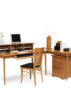 a computer desk with a laptop on top of it next to a chair and lamp