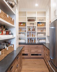 an organized pantry with lots of shelves and baskets on the counter top, along with two refrigerators