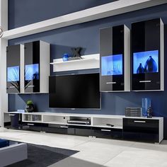 a modern living room with blue walls and white entertainment center, black furniture and large flat screen tv