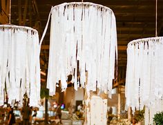 three white chandeliers hanging from the ceiling in a room filled with tables and chairs