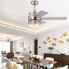 a living room with white chairs and a ceiling fan in the middle of the room