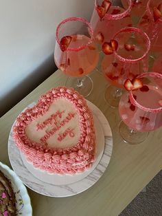 a heart shaped cake sitting on top of a table next to wine glasses and desserts