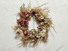 a dried flower wreath on a white towel with pink and green flowers in the middle