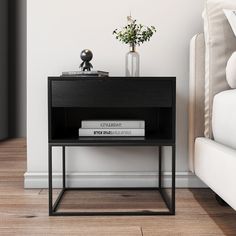 a black end table with two books and a vase on it next to a couch