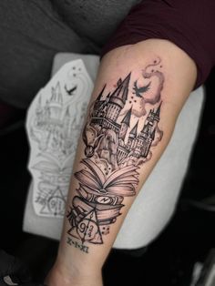 a woman's arm with a book and hogwarts castle tattoo on it