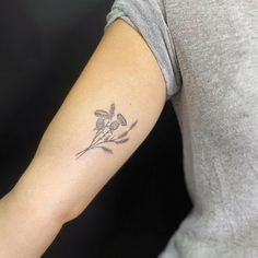 a woman's arm with a small flower tattoo on the left side of her arm