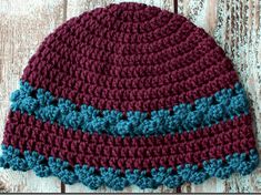 a crocheted hat with blue and red stripes on the side sitting on a wooden surface