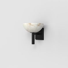 a black and white wall light with a marble bowl on the back of it's arm