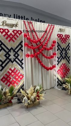 three red and white beaded curtains with plants on them in front of a wall