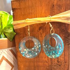 These beautiful blue earrings are inspired by the sea. They are made of blue resin and have blue shell pieces throughout the bottom half. Ocean-inspired Blue Dangle Earrings, Blue Dangle Earrings With Ocean-inspired Style, Blue Resin Dangle Jewelry, Blue Resin Earrings For The Beach, Blue Resin Earrings For Beach, Handmade Turquoise Resin Earrings, Ocean-inspired Blue Earrings For Gifts, Ocean-inspired Blue Shell Jewelry, Turquoise Dangle Earrings In Resin