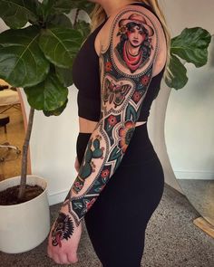 a woman with a tattoo on her arm is standing next to a potted plant