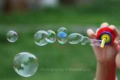 a child is blowing soap bubbles in the air with their fingers and thumbnails