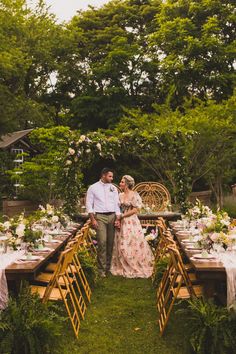 a man and woman standing next to each other at a table with flowers on it