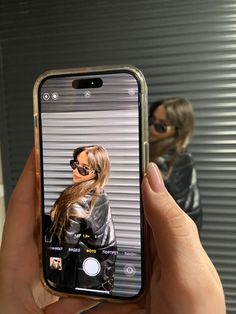 a person holding up a cell phone to take a selfie in front of a mirror