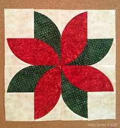 a quilted wall hanging with a red and green flower on it