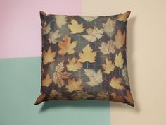 a pillow with leaves on it against a multi - colored wallpapered background in shades of brown, yellow and green