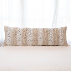 a white bed topped with a pillow next to a window