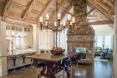 a dining room table with chairs and a bowl of fruit on it in front of a fireplace