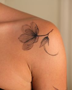 the back of a woman's shoulder with a flower tattoo on her left arm