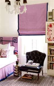 a bedroom decorated in pink and purple with a bed, chair, chandelier, bookshelf and window