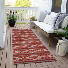 a red and white rug sitting on top of a wooden floor next to a bench