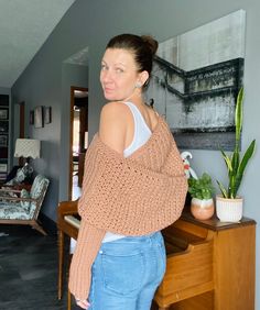 a woman is standing in front of a piano and looking at the camera while wearing jeans