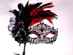 Masquerade mask, masquerade mask with stick and feathers, laser cut metal mask black and red crytals This a stunning masquerade metal laser cut mask with absolutely gorgeous rooster red feathers a black flower and a black stick and red matching beautiful gems.  If you wish this same style and design of mask to be without the stick please feel free to contact me I will be happy to make the change!  In my store I have a large variety of masquerade metal laser cut mask for masquerade ball parties, I have lace machine embroidered masquerade mask I embroider too and if you wish for the thread to be changed to match the occasion please feel free to contact me anytime!  In my store I have other designs of masks and metal laser cut with different designs and colors of gems and masks also items tha Black Masks For Carnival, Venetian Black Masquerade Mask, Black Masks And Prosthetics For Carnival, Black Masks And Prosthetics For Carnival Gift, Red Fantasy Party Mask, Red Masquerade Mask For Mardi Gras Gift, Red And Black Masquerade Mask, Mask For Masquerade Ball, Masquerade Mask With Stick