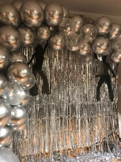 silver balloons and streamers hanging from the ceiling in front of a mirror ball backdrop