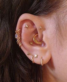 a close up of a person's ear with gold stars and moon piercings