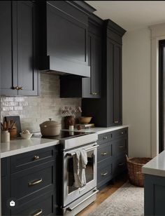 a kitchen with black cabinets and white counter tops, along with an oven in the center