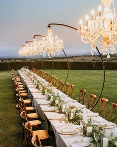 a long table is set up with white linens and greenery for an elegant dinner