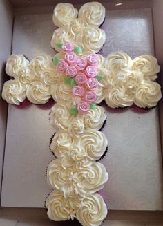 the cupcakes are decorated like a cross with pink roses on it and green leaves