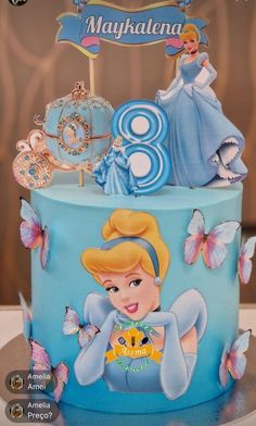 there is a blue cake decorated with princesses and butterflies on it's side