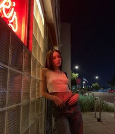 a woman leaning against a wall with her hand on her hip