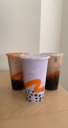 three iced coffee drinks sitting on top of a wooden table