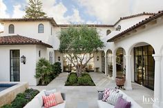 an outdoor living area with couches, tables and a pool in the middle of it