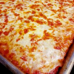 a large cheese pizza sitting on top of a metal baking pan in an oven with one slice missing